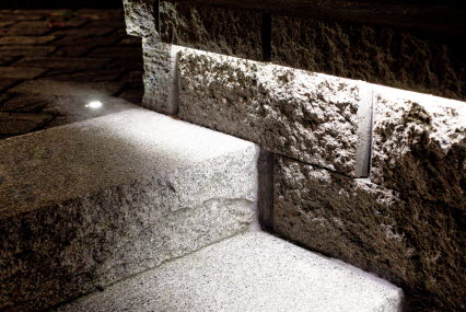 Blockstenstrappa i granit flankerad av en Brilliant mur smakfullt upplyst av en LED-slinga och infällda spotlights.